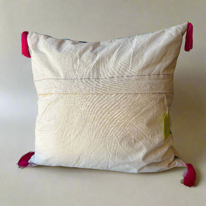 Rear view of the Rainforest cushion showing the plain cream back with an envelope opening, raspberry tassels at the corners and an Apricot Moon tag