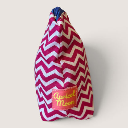 End view of the Raspberry Chevron everyday pouch showing the Apricot Moon label and a navy blue zip