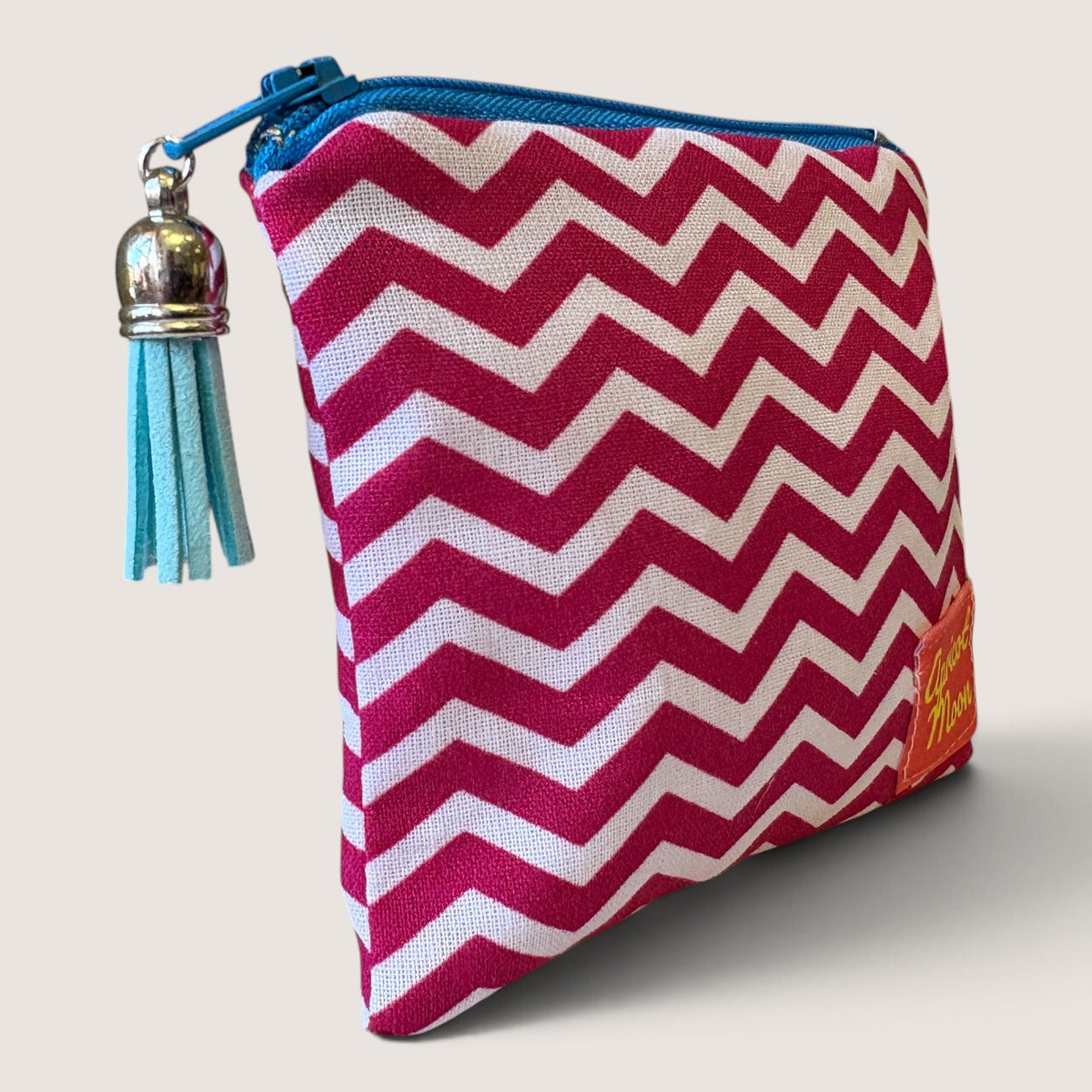 Raspberry Chevron coin purse angled to show the pink and white chevron print, bright blue zip and pale blue suede tassel with a silver cap