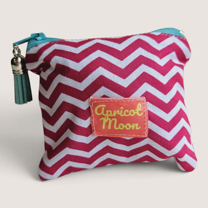 Raspberry Chevron coin purse in a pink and white chevron print with the Apricot Moon label, a teal zip and a dark teal suede tassel