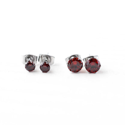 Pair of silver stud earrings with red gemstones on a white background