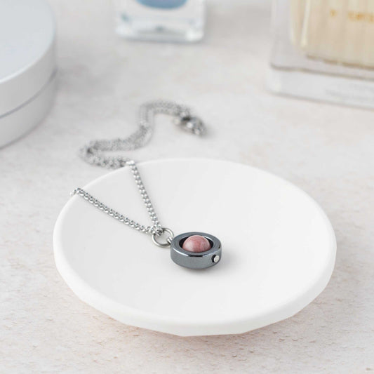 Silver necklace with a pink pendant on a white dish