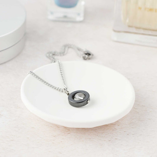 Necklace with a round pendant on a white dish