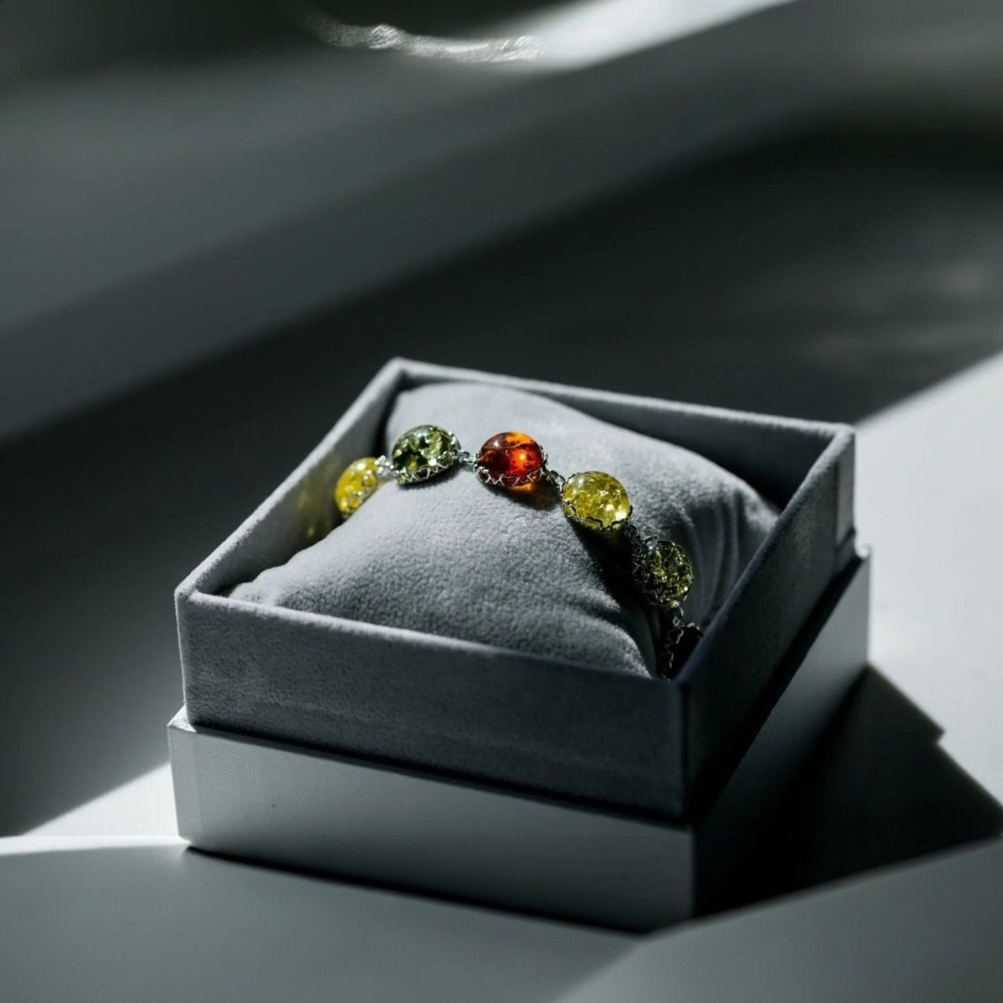 Ring with multicolored gemstones in a gray jewelry box on a light surface.