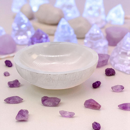 White selenite crystal bowl with purple crystals on a light background