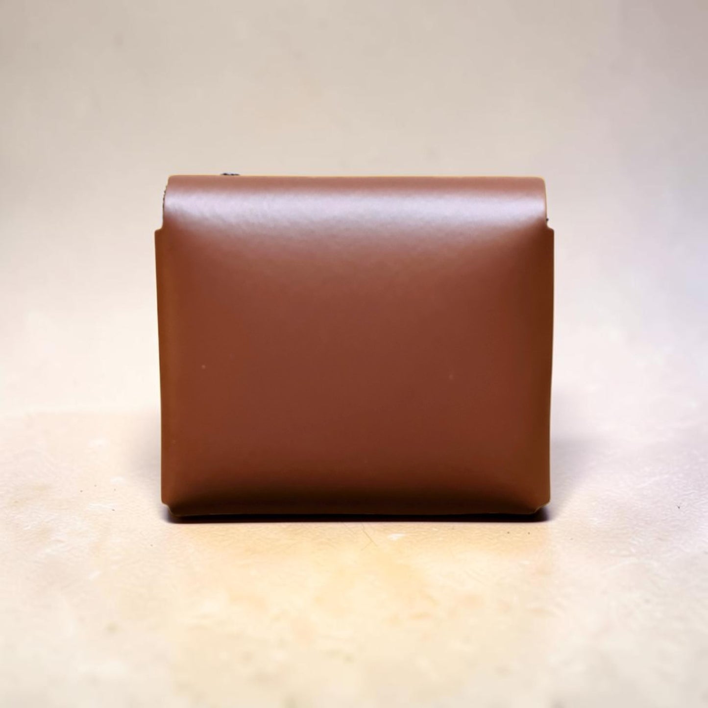 Brown leather clutch bag on a light beige background