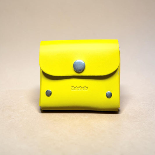 Yellow leather wallet with silver buttons on a beige background