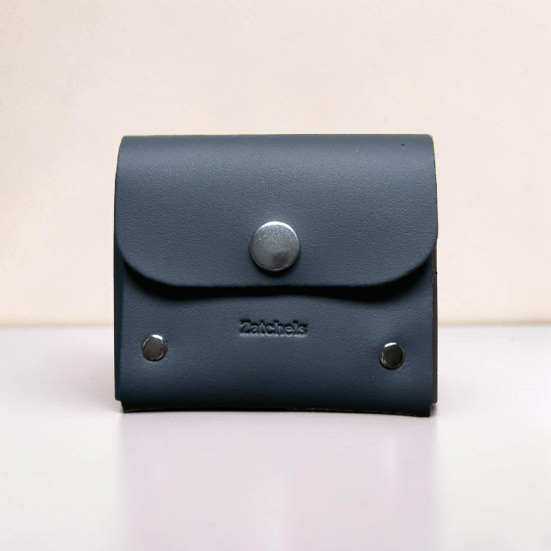 Black leather wallet with silver buttons on a light background