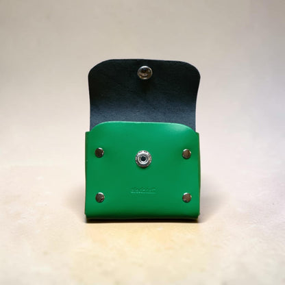 Green leather wallet with black flap on a light gray background