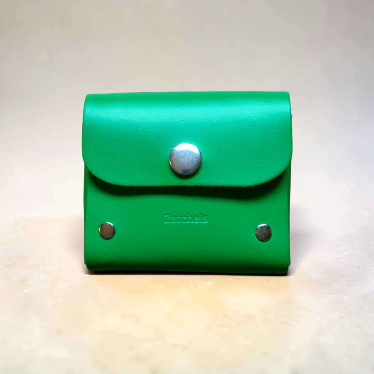 Green leather wallet with silver buttons on a light background