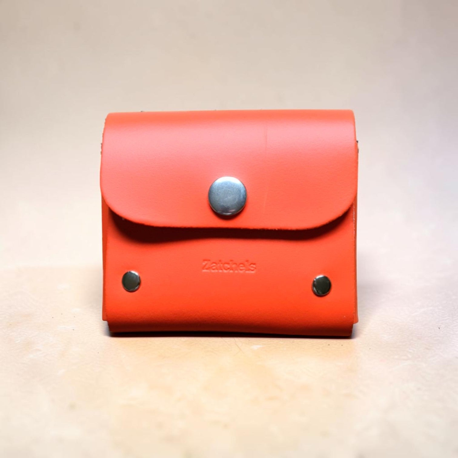 Red wallet with a metallic button on a beige background