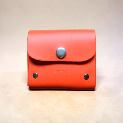 Red wallet with a metallic button on a beige background