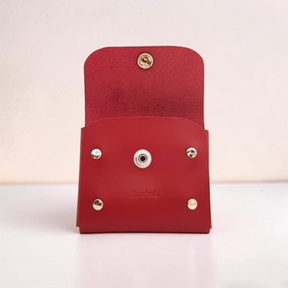 Red leather wallet with gold and silver accents on a light pink background