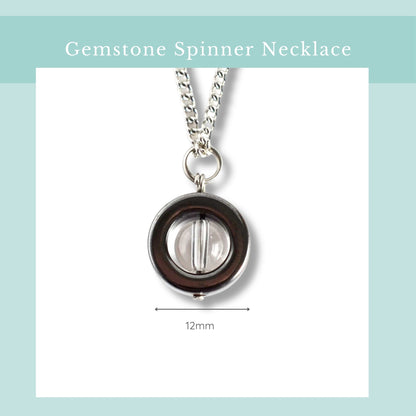 Gemstone spinner necklace with a clear gemstone on a light blue background