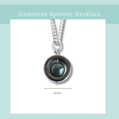 Gemstone spinner necklace with a blue gemstone on a light blue background