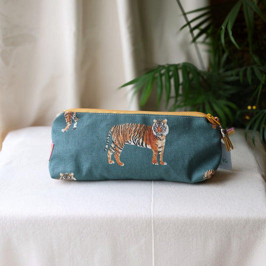 Tiger Tiger pencil case with a mustard yellow zip on a cream cloth beside a palm plant