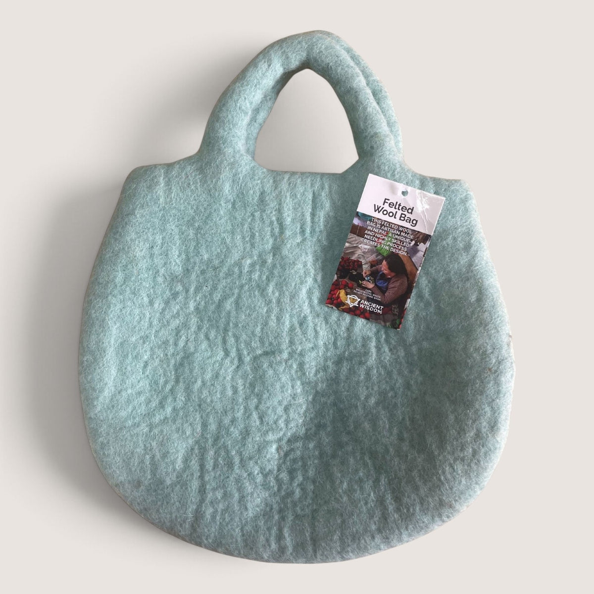 Back of the Tree and Beehive Felted Bag in plain pale turquoise felt with an Ancient Wisdom hang tag