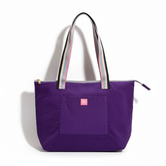 Twilight Bloom shoulder tote in purple corduroy with rainbow striped handles and a pink Apricot Moon label on the front pocket, front view on a white background, handmade in Dorset