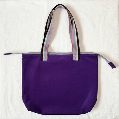 Rear view of the Twilight Bloom purple corduroy shoulder tote with striped handles and no pocket, laid flat on a cream cloth