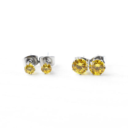 Pair of silver stud earrings with yellow gemstones on a white background