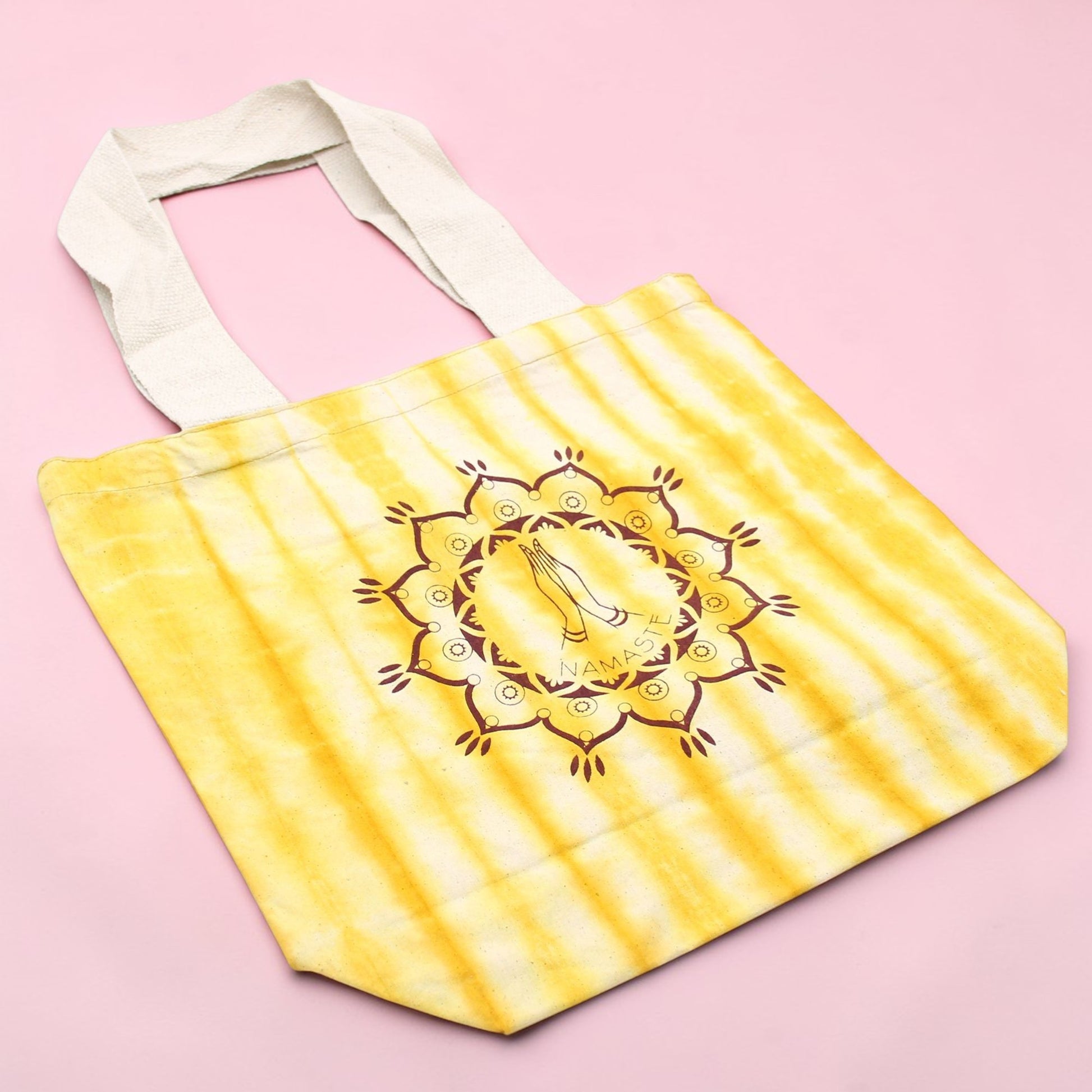 Yellow tote bag with a mandala design on a pink background