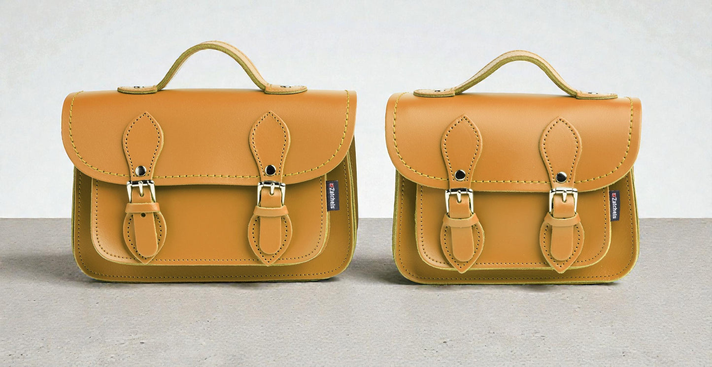 Two mustard yellow leather bags with gold buckles on a light gray background