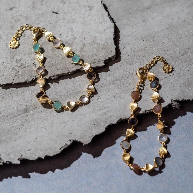 Gold bracelet with gemstones on a textured stone surface
