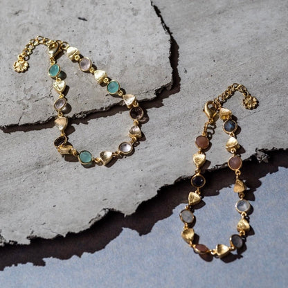 Gold bracelet with gemstones on a textured stone surface