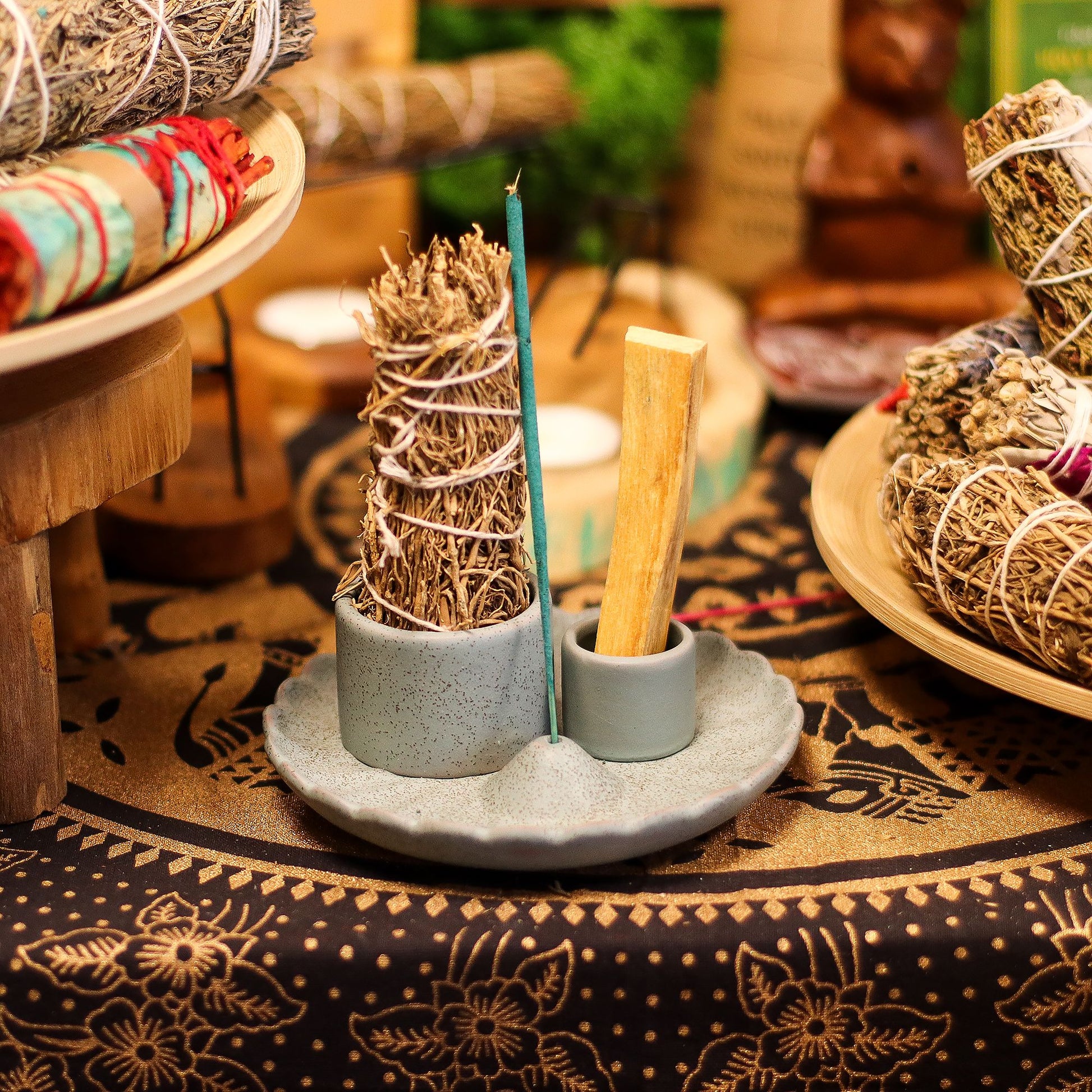 Incense sticks and cones on a ceramic holder with a patterned tablecloth in the background