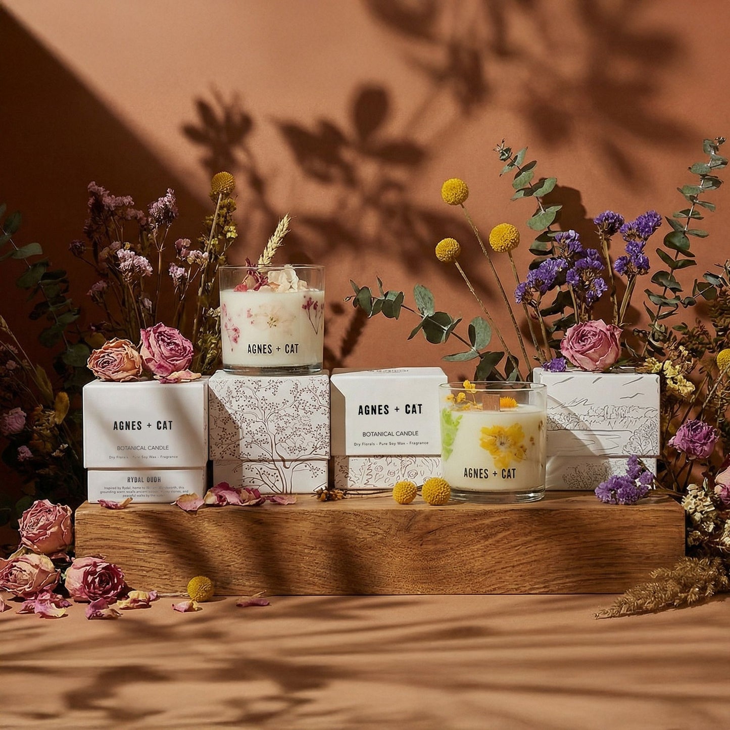 Candles with floral packaging on a wooden stand against a warm brown background