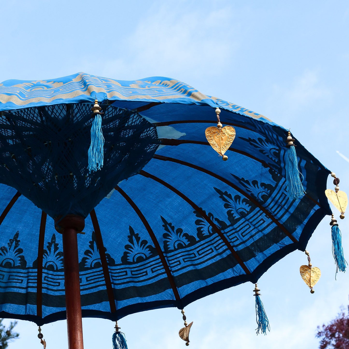Decorative blue umbrella with tassels against a clear sky