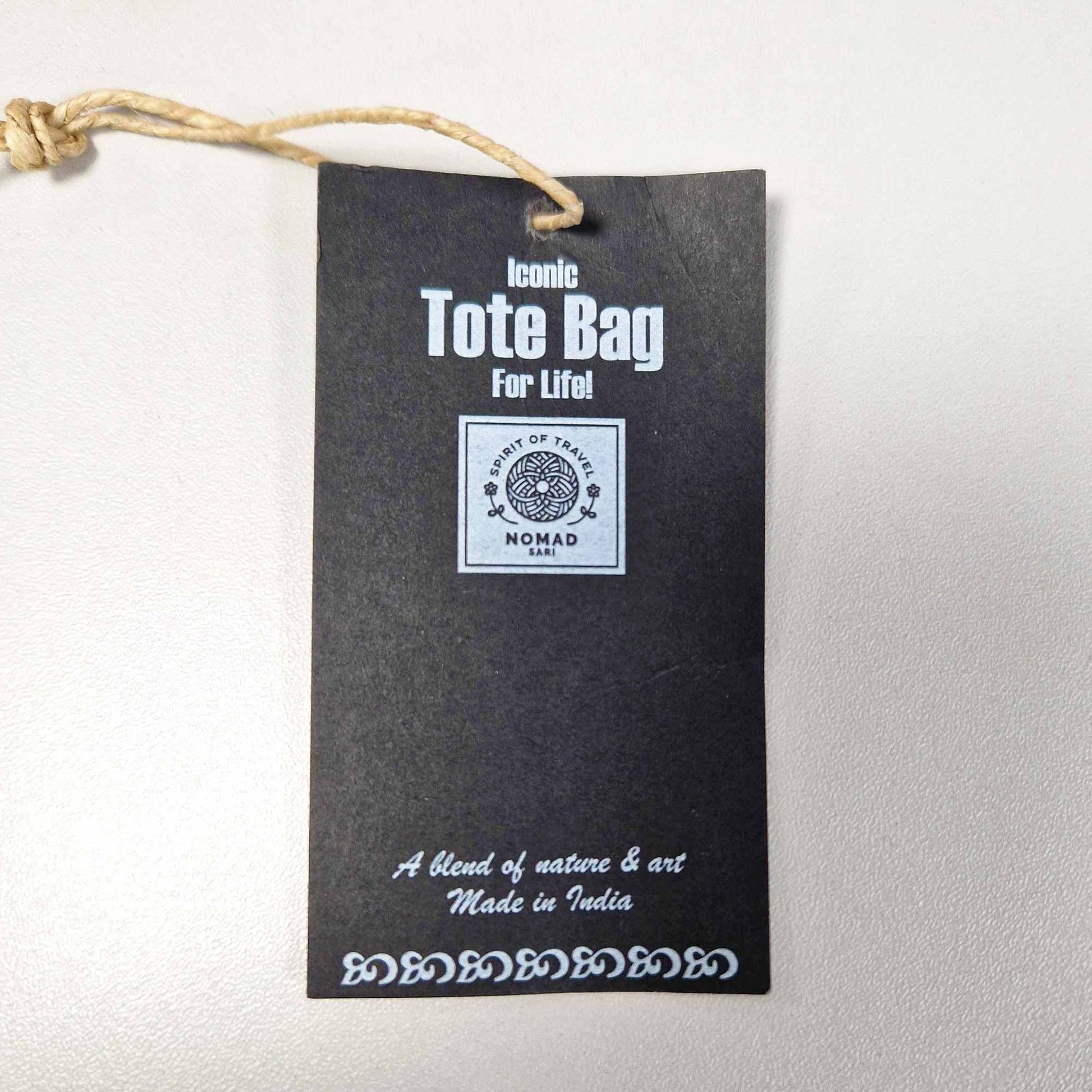 Black tote bag label with white text on a light gray background