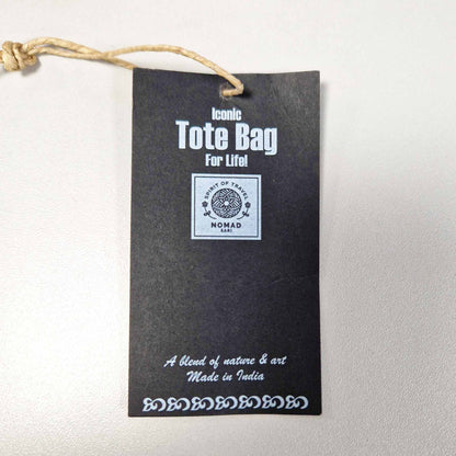 Black tote bag label with white text on a light gray background