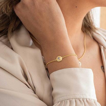 Close-up of a person wearing a gold bracelet with a circular design.