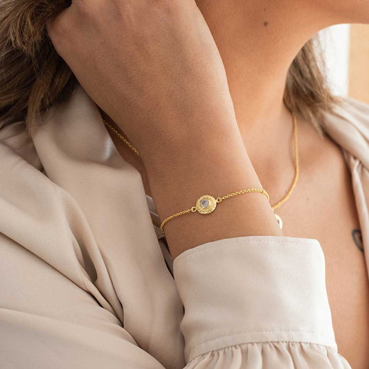 Close-up of a person wearing a gold bracelet with a circular design.
