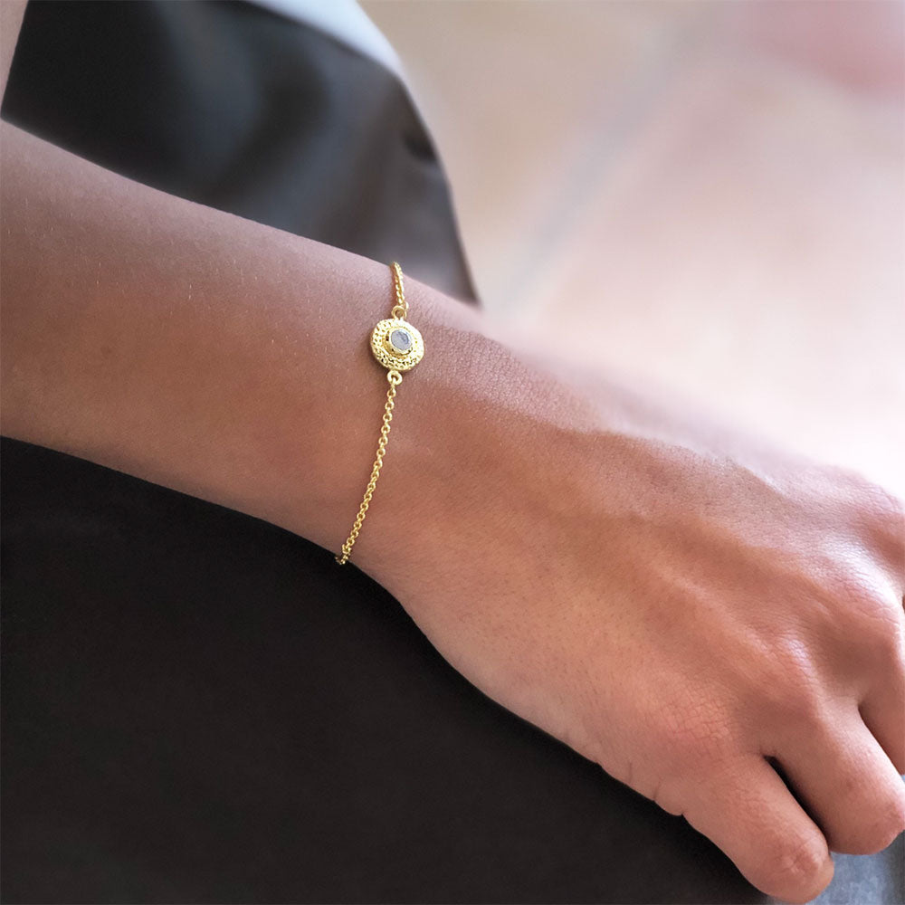 Gold bracelet on a wrist with a blurred background