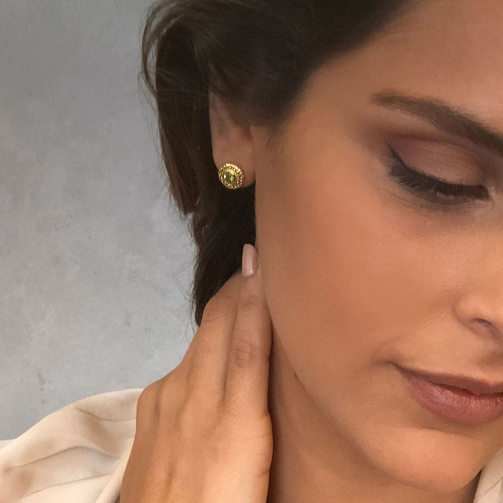 Close-up of a woman wearing gold earrings with a neutral background