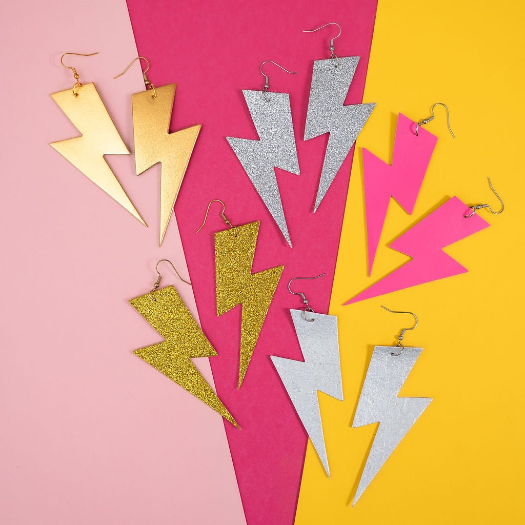 Colorful lightning-shaped earrings on a pink and yellow background