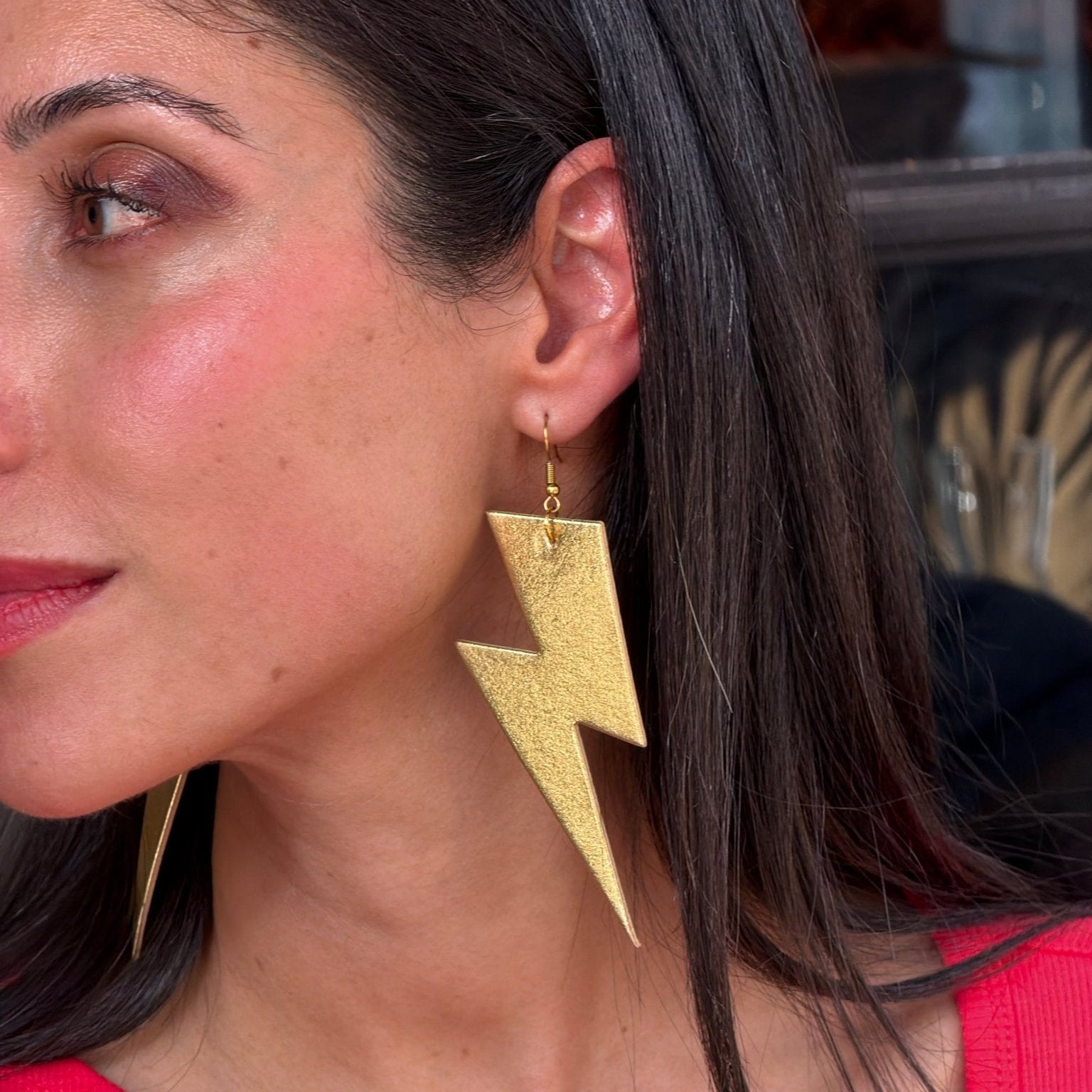 Close-up of a woman wearing gold lightning bolt earrings.