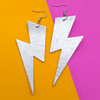 Silver lightning bolt earrings on a colorful background