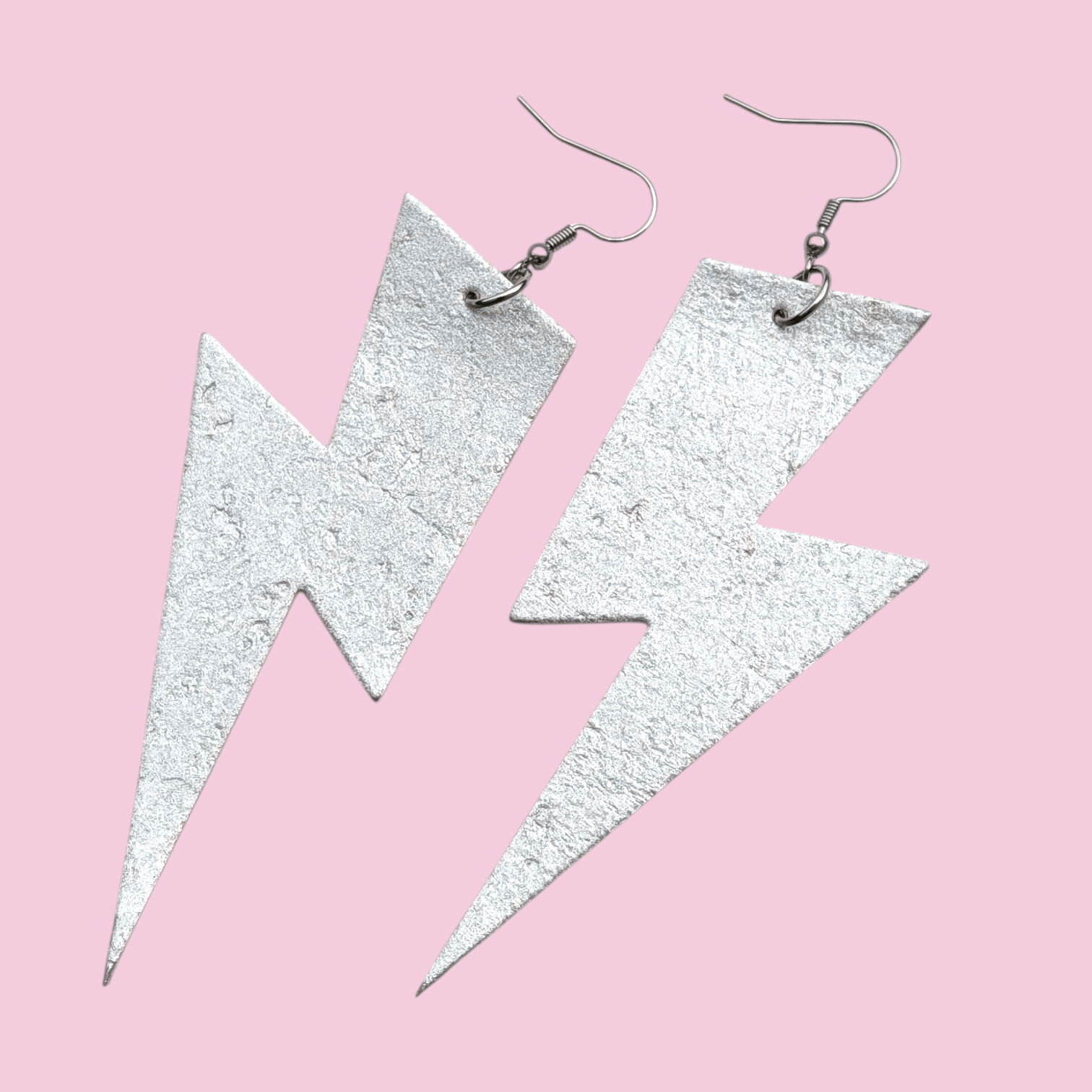 Silver lightning bolt earrings on a pink background