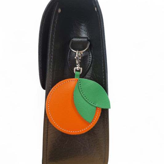 Orange and green keychain attached to a black leather bag.