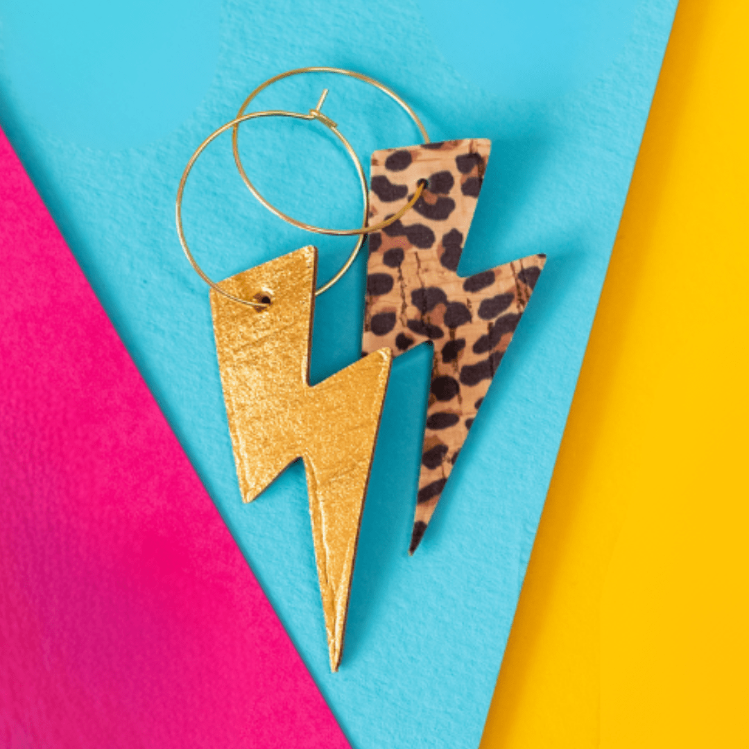 Gold lightning bolt earrings with leopard print on a colorful background