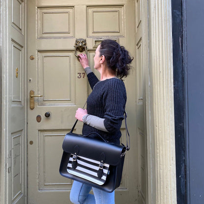 Woman with a black satchel bag standing in front of a door