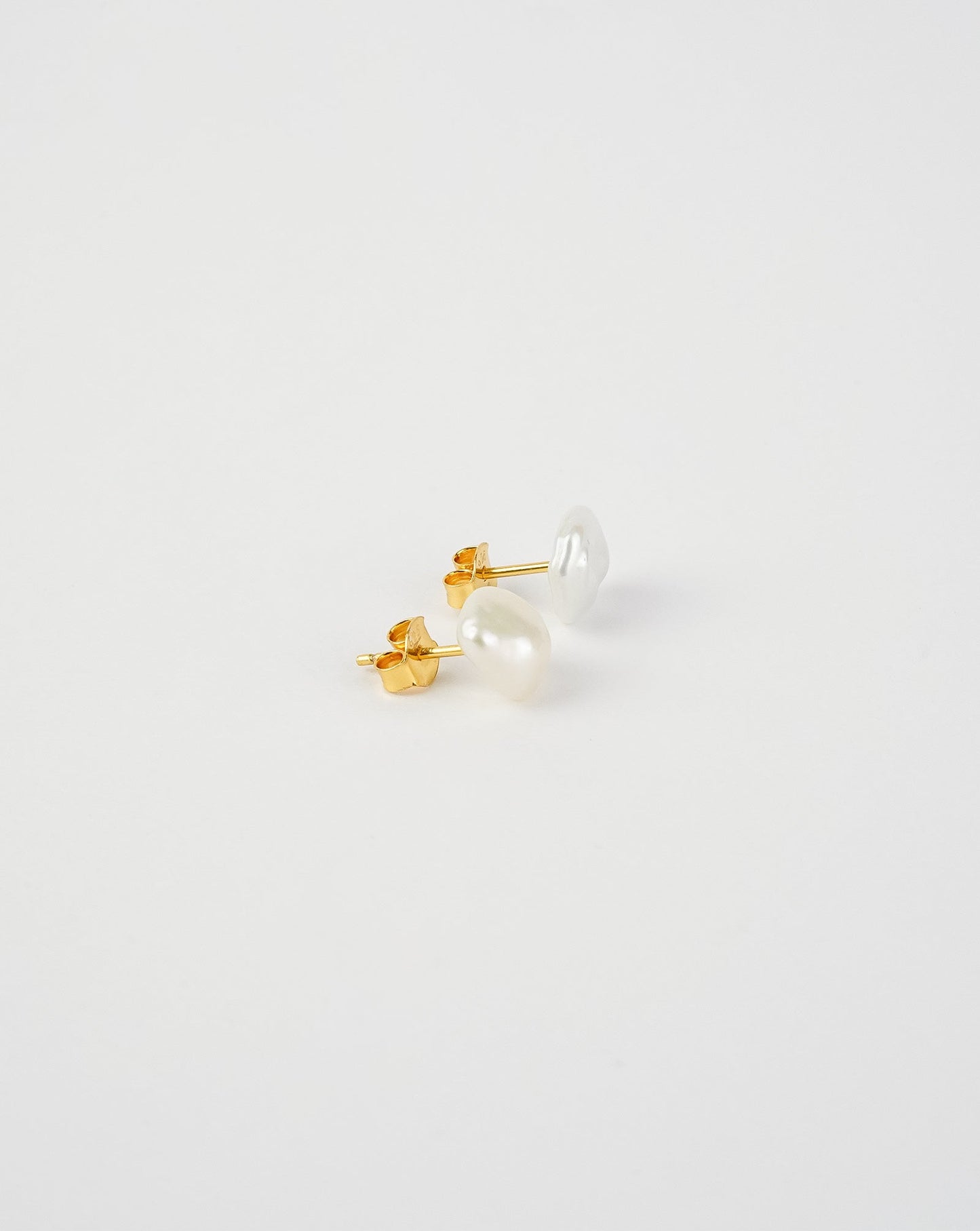 Pair of pearl stud earrings on a light gray background