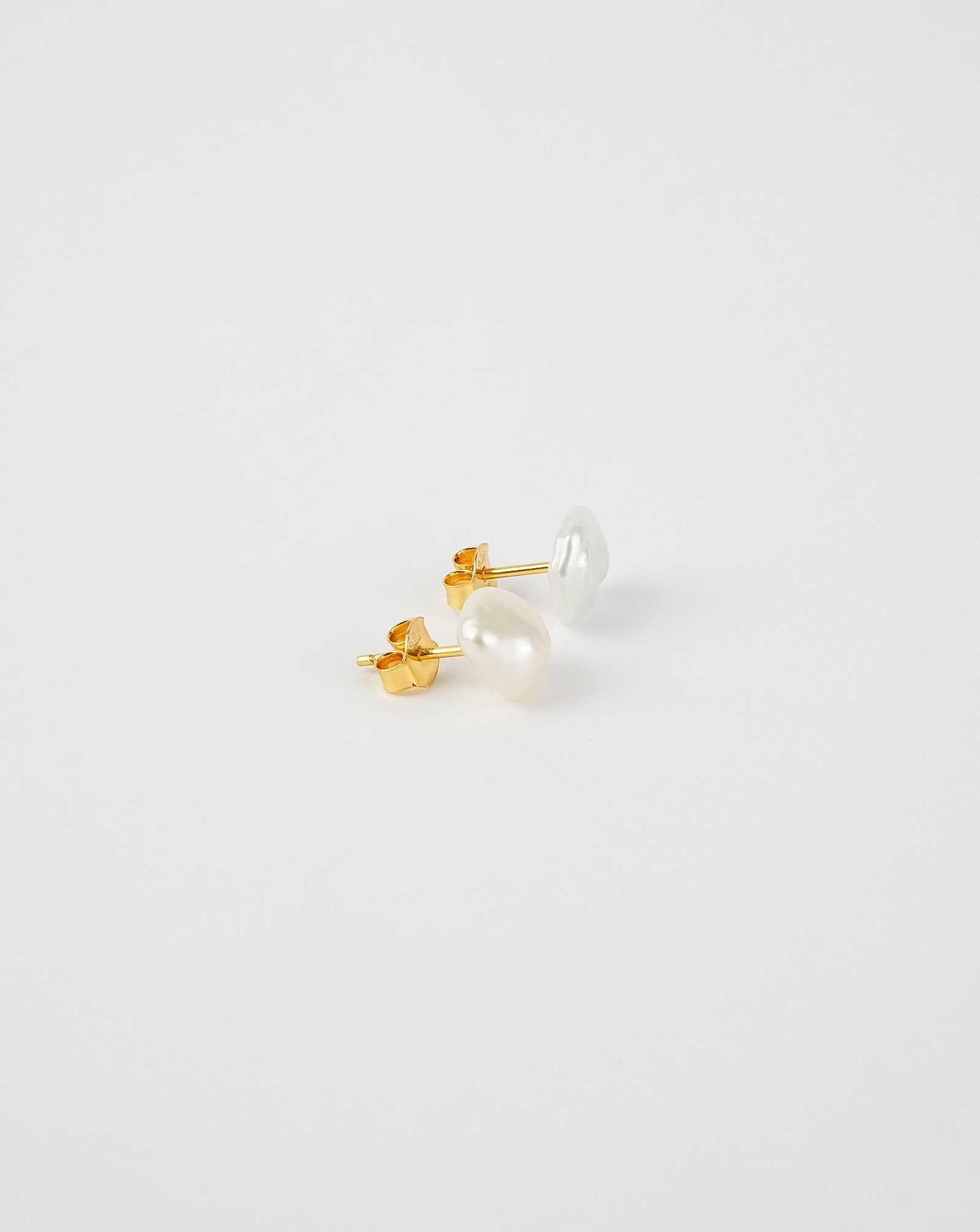 Pair of pearl stud earrings on a light gray background