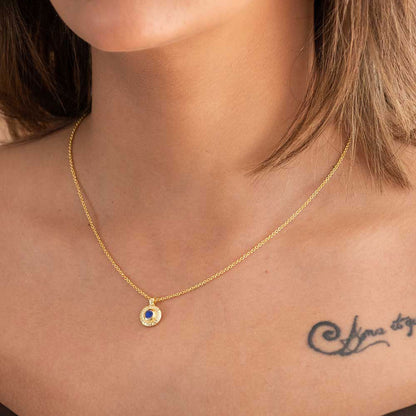Gold necklace with a blue gemstone on a person's neck