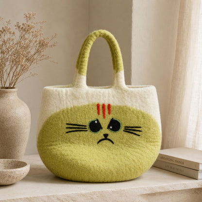 Large Grumpy Cat Felted Bag on a pale shelf beside a vase of dried flowers and a stack of books