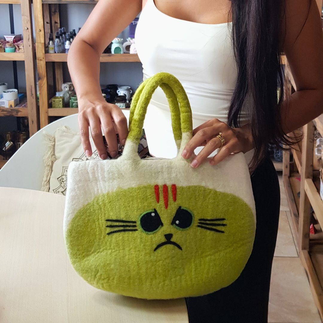 Woman holding the Large Grumpy Cat Felted Bag open and putting a purse inside, showing how roomy it is