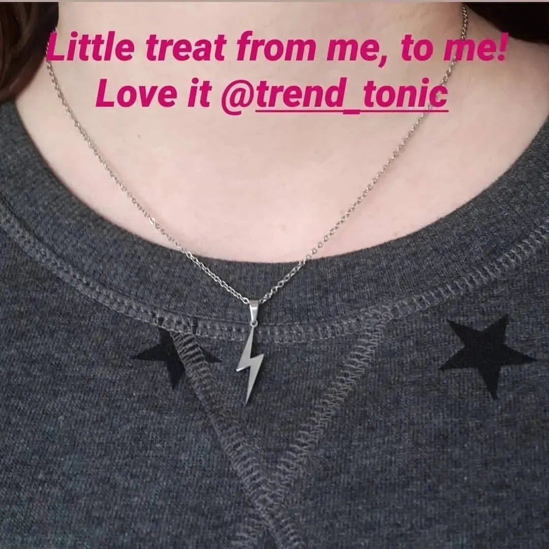 Necklace with a lightning bolt pendant on a gray shirt, with text overlay.